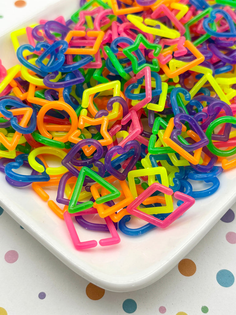 A white plate filled with a colorful assortment of plastic shapes, including various geometric and heart-shaped designs, creating a vibrant and playful visual display.