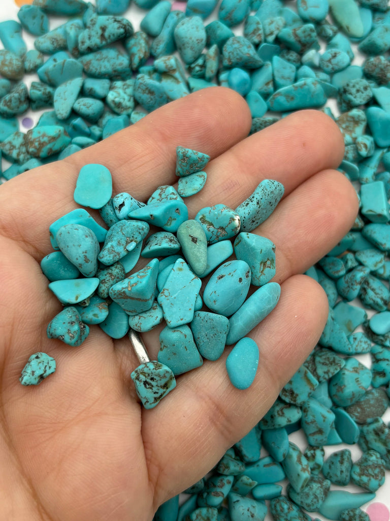 a person is holding a handful of turquoise stones