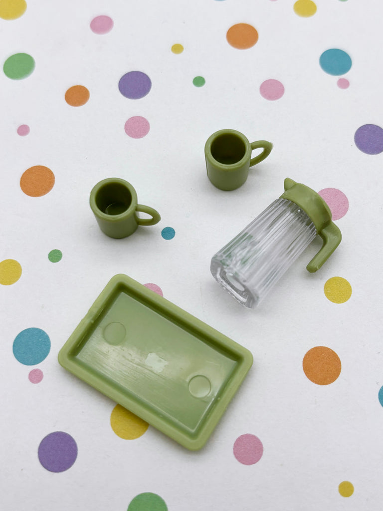 a collection of green cups and a clear pitcher, all arranged on a white background with colorful polka dots.