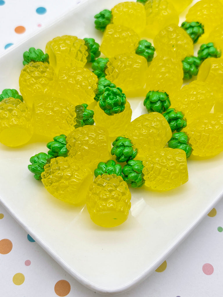 A white plate filled with yellow and green gummy fruit-shaped candies, resembling pineapples.