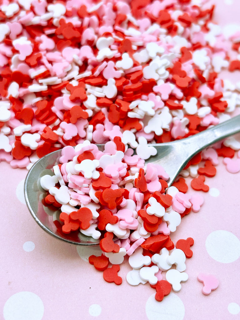 a spoon full of red, white and pink sprinkles