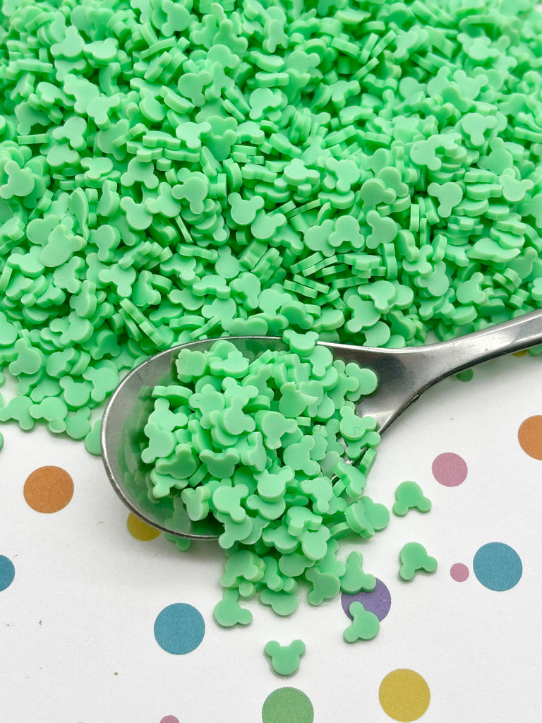 a spoon filled with green sprinkles on top of a polka dot table