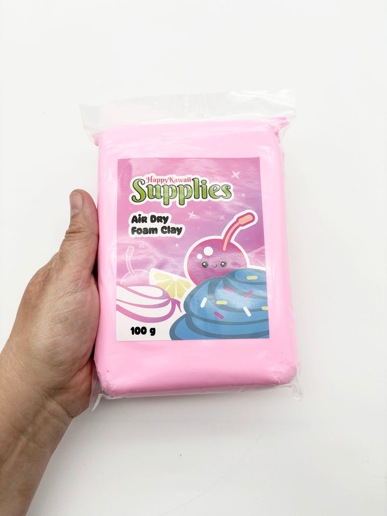 A hand holding a package of pink air day foam clay.