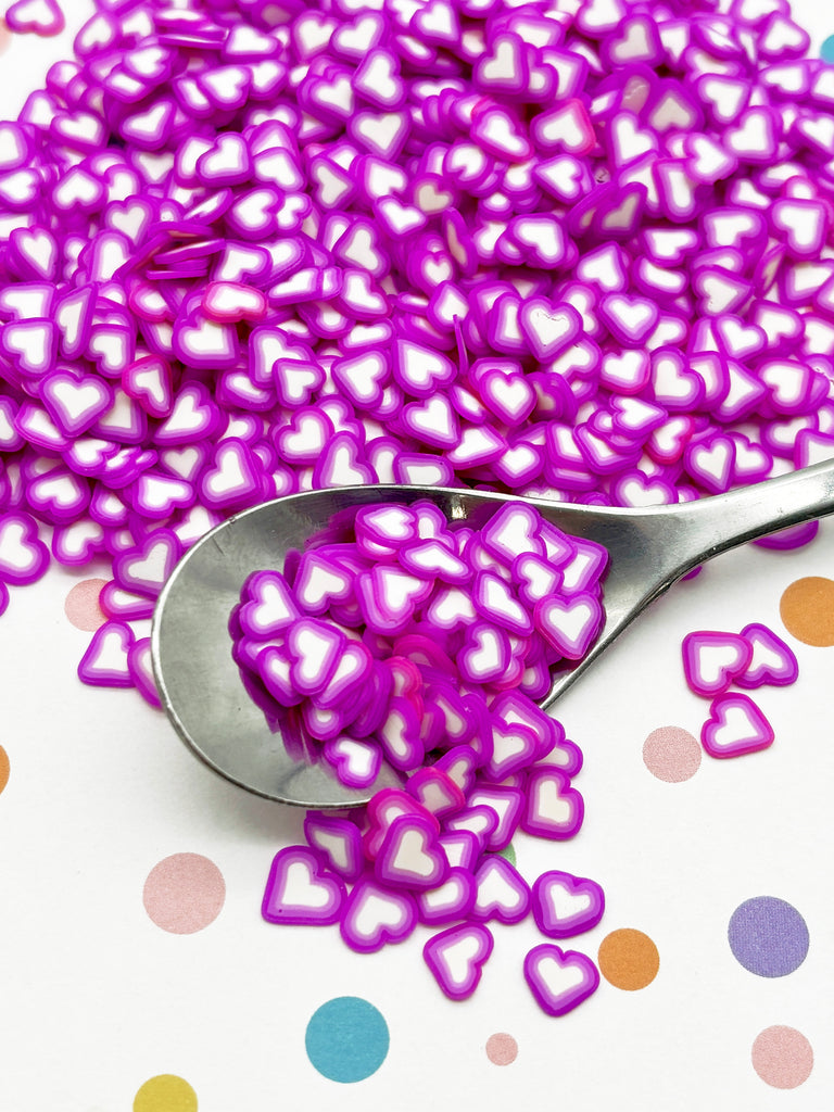 a spoon filled with purple hearts on top of a table