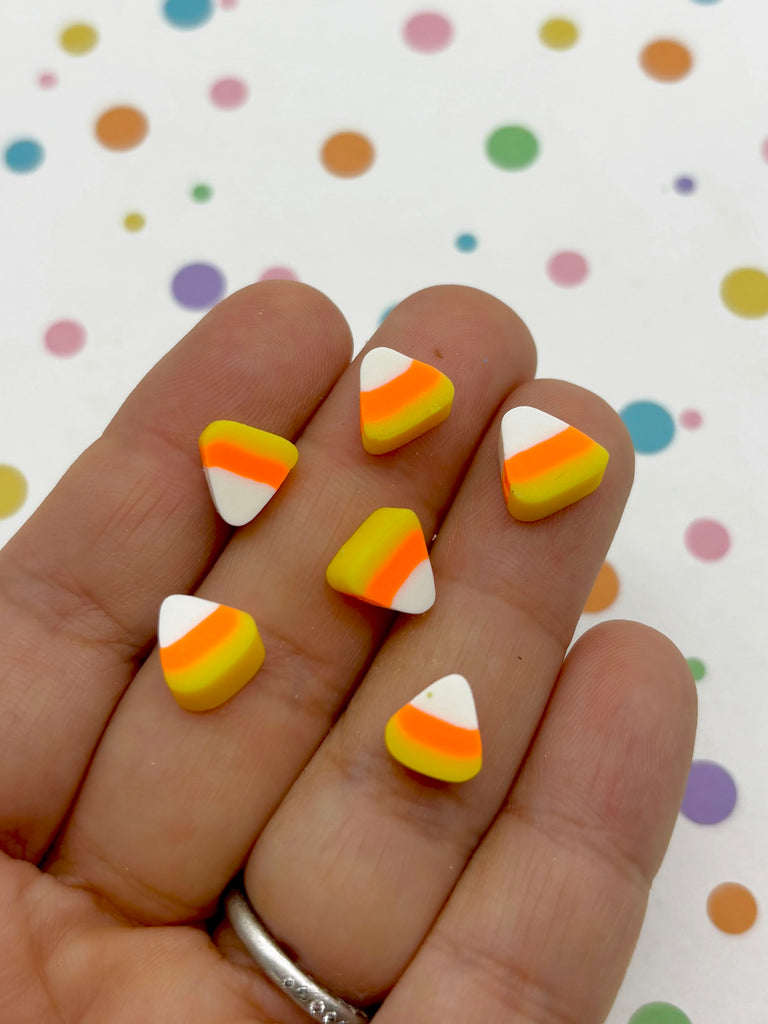 a hand holding a yellow and white striped manicure