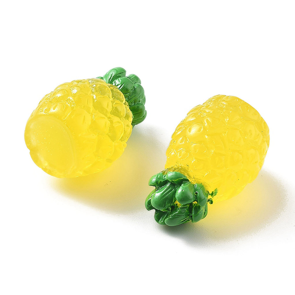 Two yellow pineapple-shaped objects with green tops are placed on a white background.