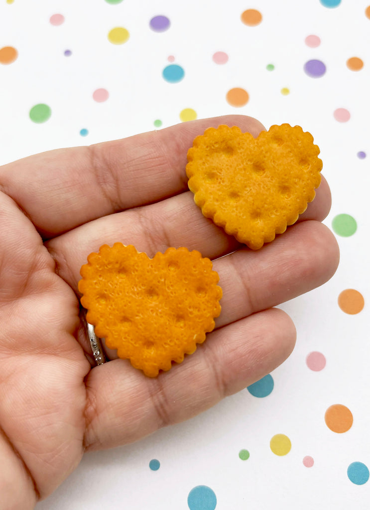 A hand holding two heart-shaped crackers against a background with colorful polka dots.