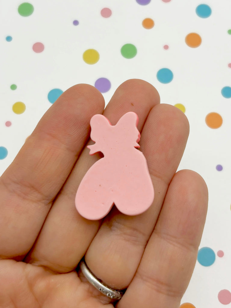 a person holding a pink bear shaped object in their hand