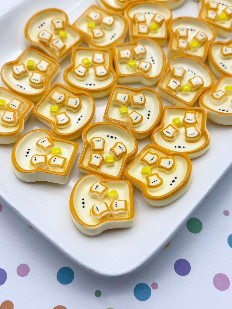 a white plate with a variety of yellow and orange-colored breakfast food items, including what appear to be toast or bread pieces, arranged on it.