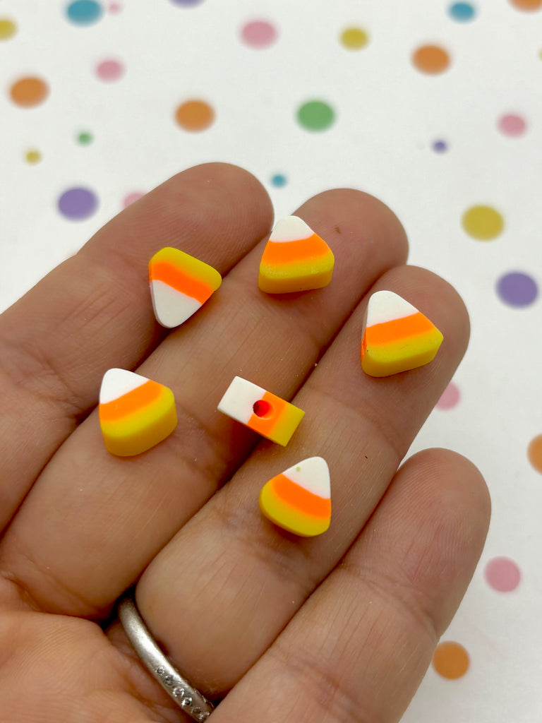 a hand holding a small orange and white candy corn