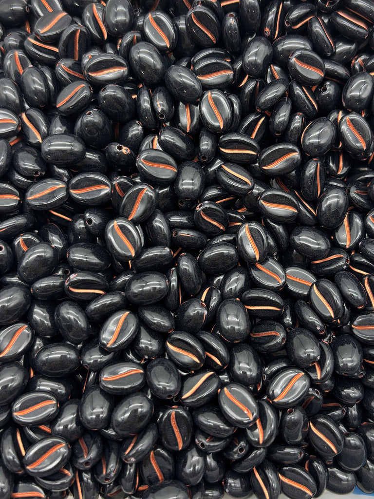 a close-up view of a large pile of black beads with orange stripes, creating a visually striking contrast.