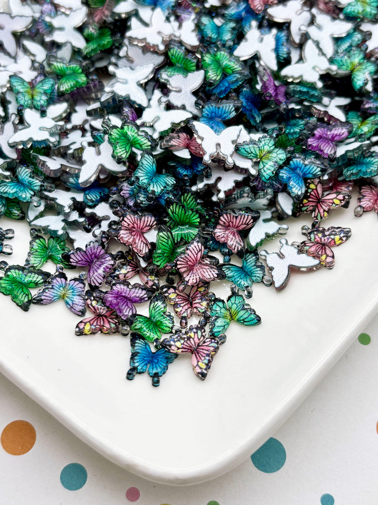 a white plate with a variety of colorful butterfly-shaped objects, including white, green, purple, and pink butterflies, scattered across the plate.