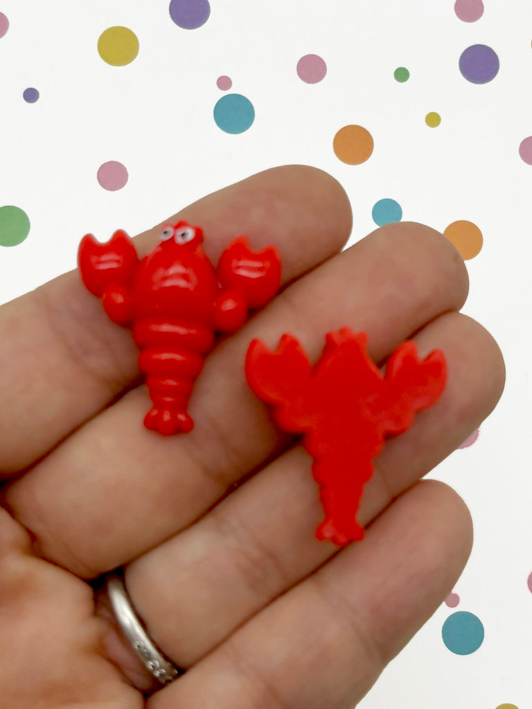 a hand holding two small red plastic animals