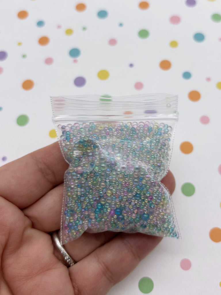 A hand holding a small bag filled with multicolored beads against a background with colorful polka dots.