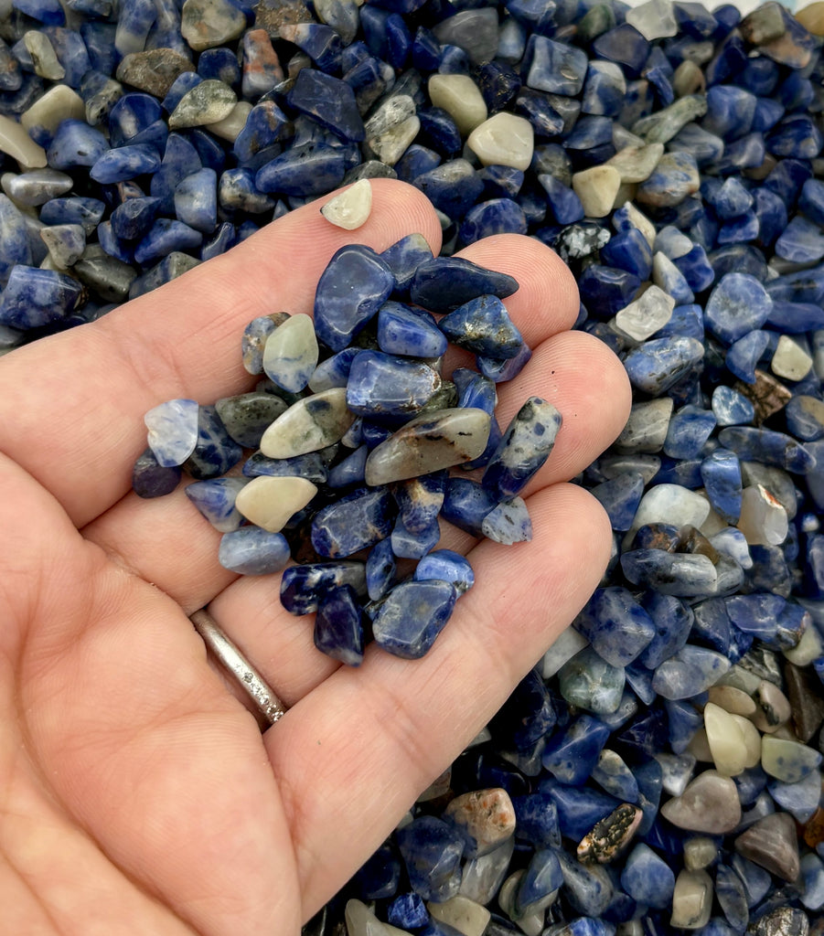 a hand holding a handful of blue and white rocks