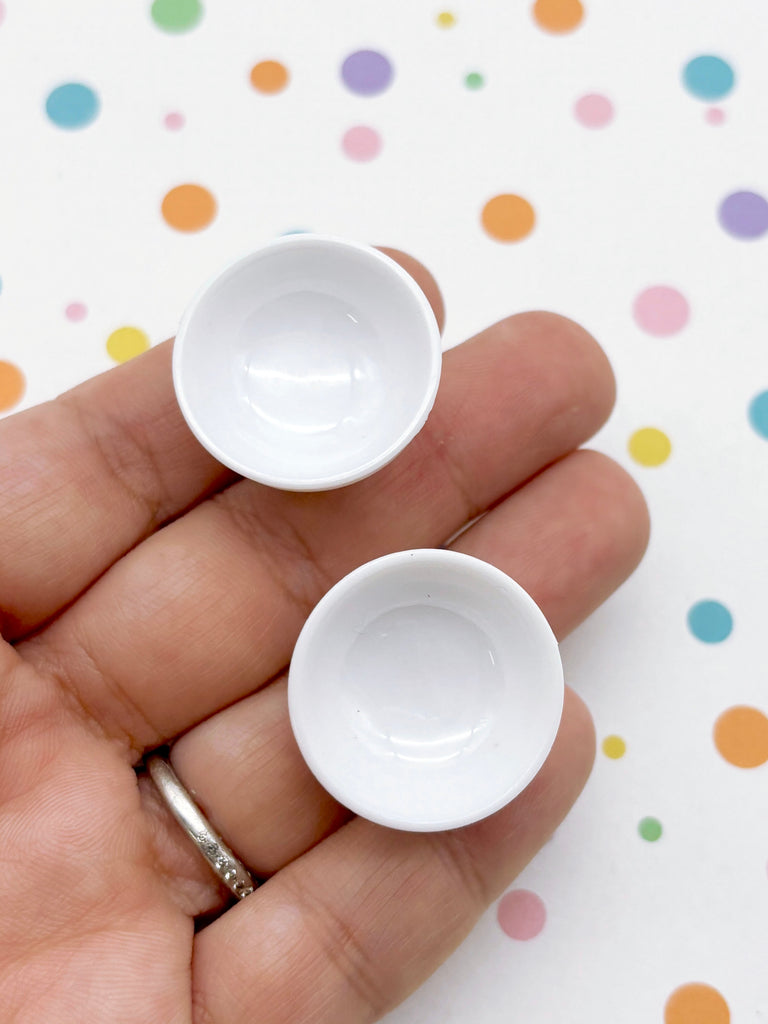 A hand holding two white bowls against a background with colorful polka dots.