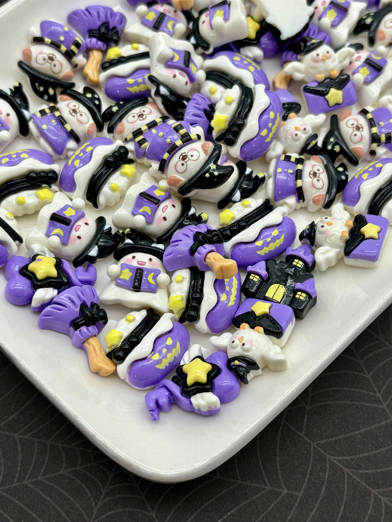 a white plate filled with various purple and black decorative objects, including small figurines, stars, and other whimsical designs.