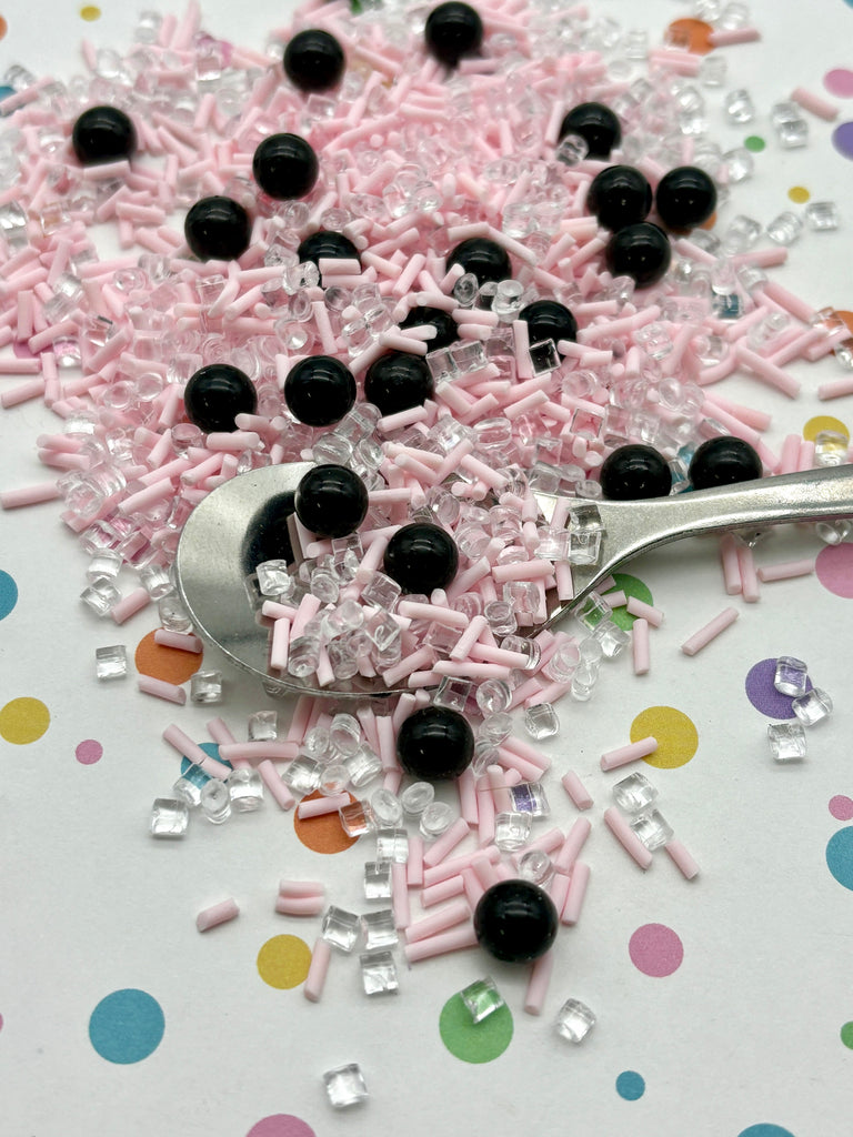 a spoon full of pink and black sprinkles