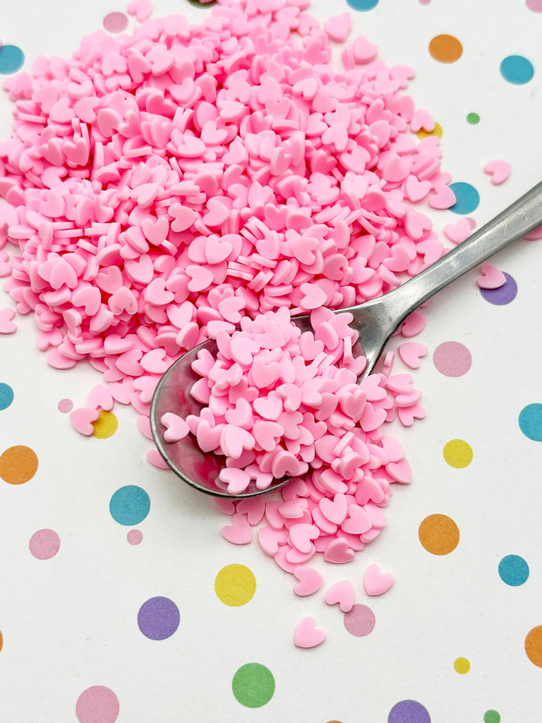 a spoon filled with pink sprinkles on top of a table