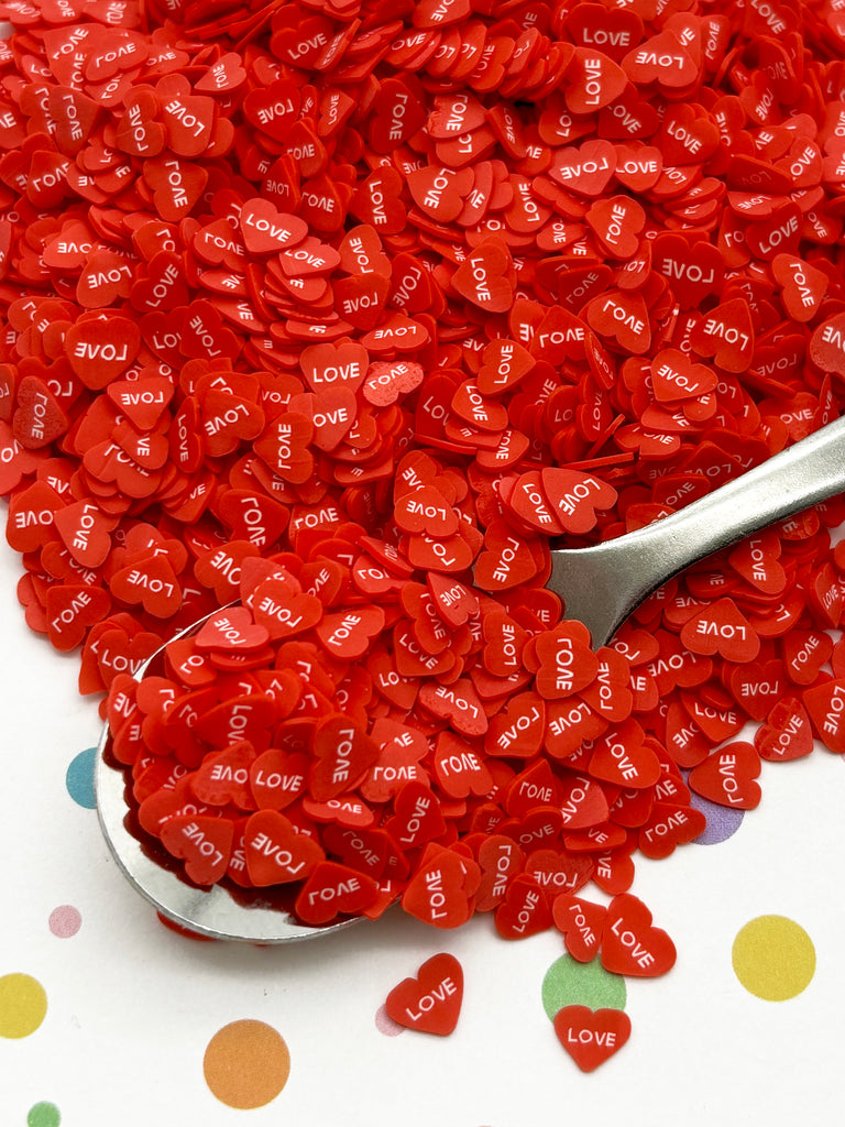 a spoon sitting on top of a pile of red hearts