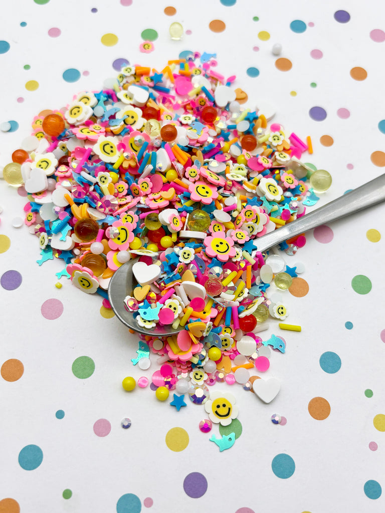 A pile of colorful sprinkles, including smiley faces, on a white background with polka dots.