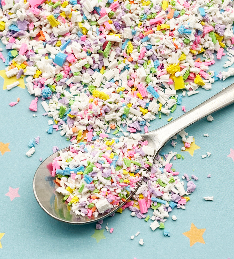 a spoon full of sprinkles on a blue surface