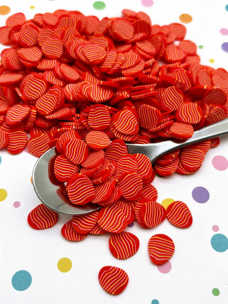 a pile of red hearts sitting on top of a table next to a spoon