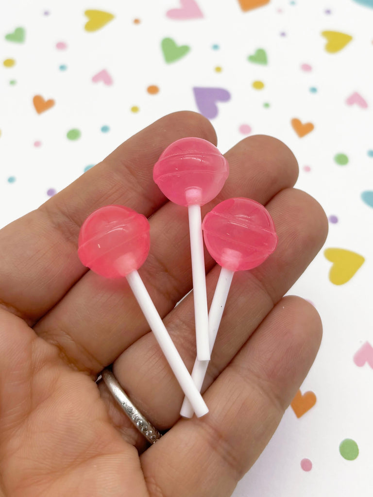 a person holding two candy lollipops in their hand