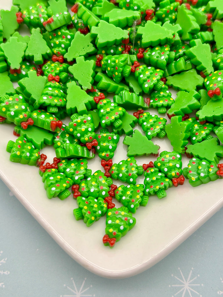 a white plate filled with green and red Christmas tree-shaped candies, arranged in a festive manner.