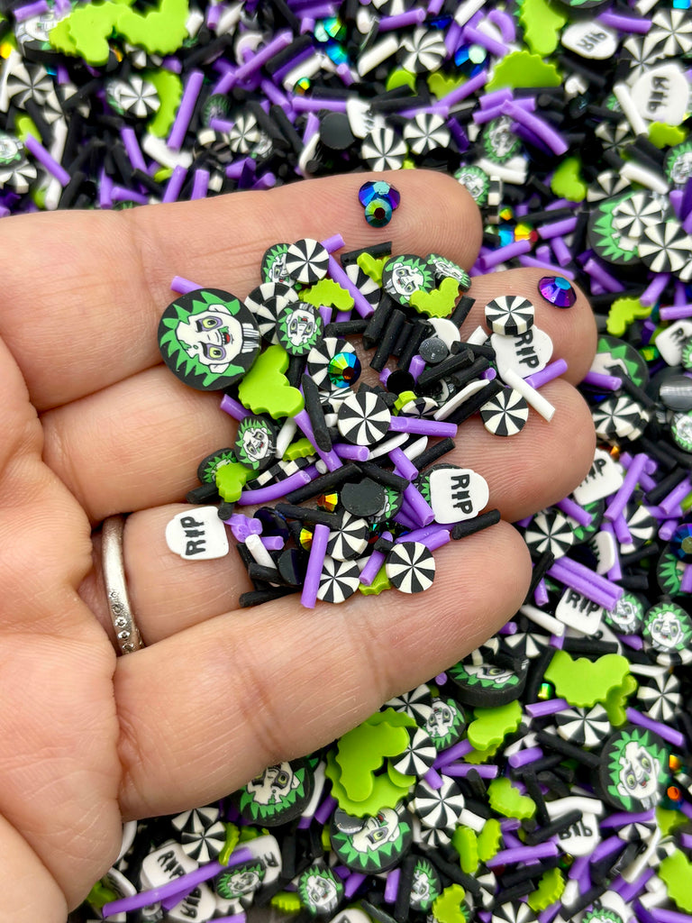 a hand holding a pile of purple and green sprinkles