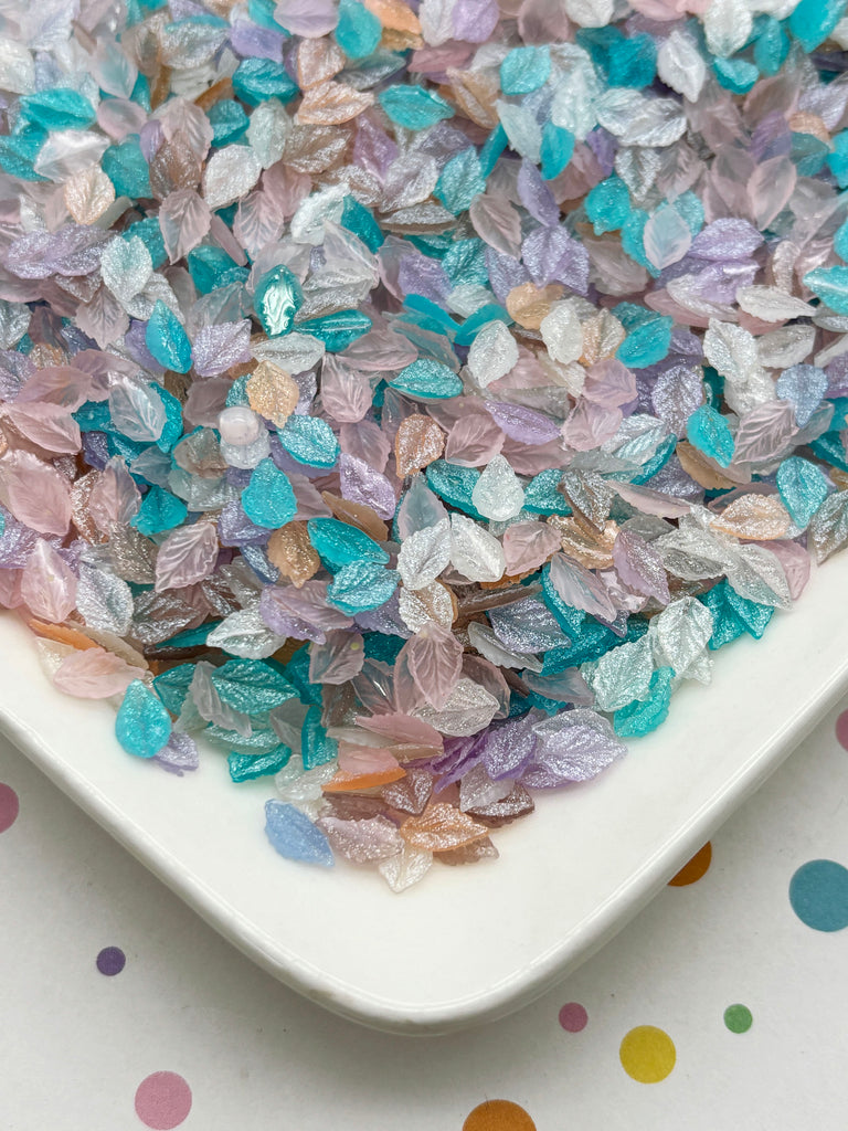 a white plate filled with multicolored, glittery, and shiny objects resembling leaves or petals, scattered across the plate.