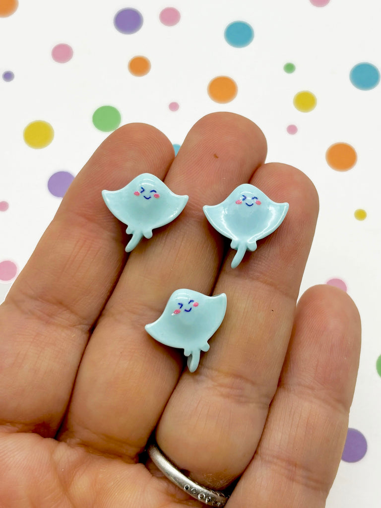 a person is holding two small white ghost earrings