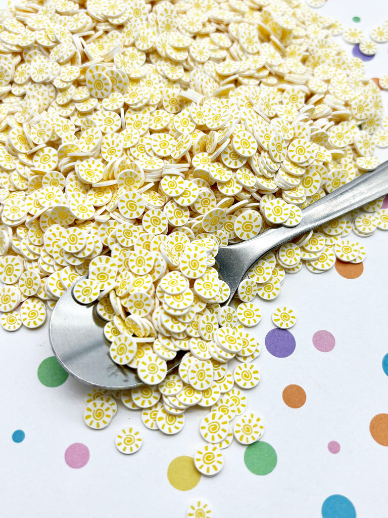 a pile of yellow and white flowers next to a spoon