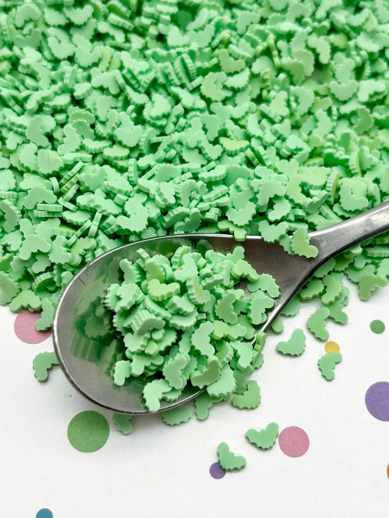 a spoon filled with green sprinkles on top of a table