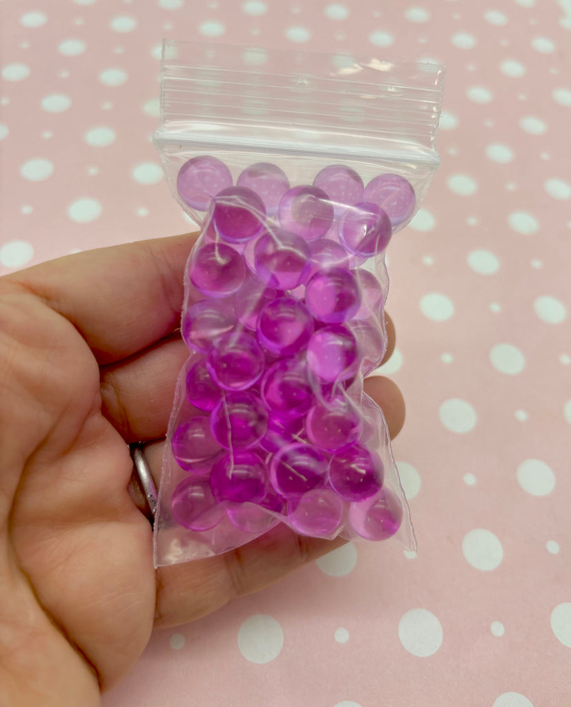 a hand holding a bag of purple plastic buttons