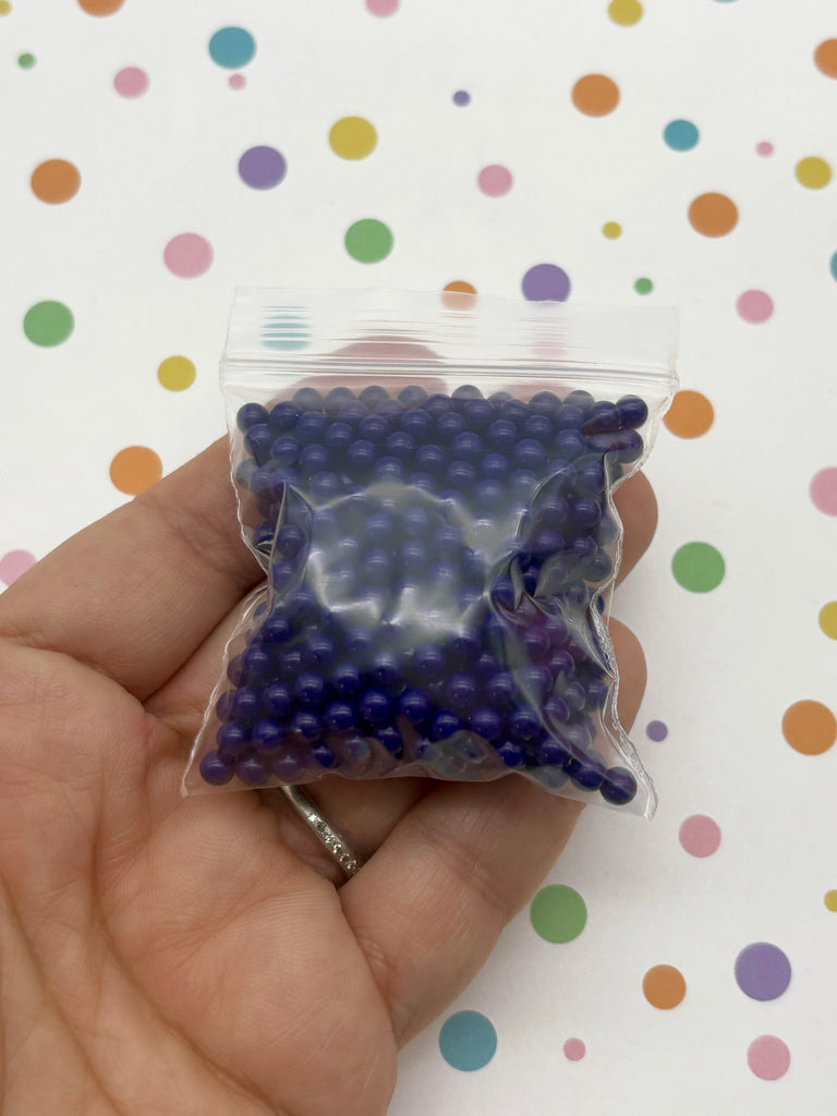 a hand holding a bag of purple and blue beads