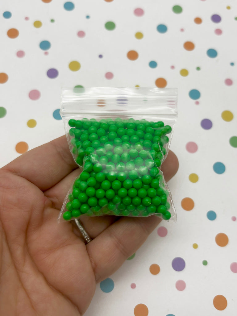 a hand holding a bag of green beads