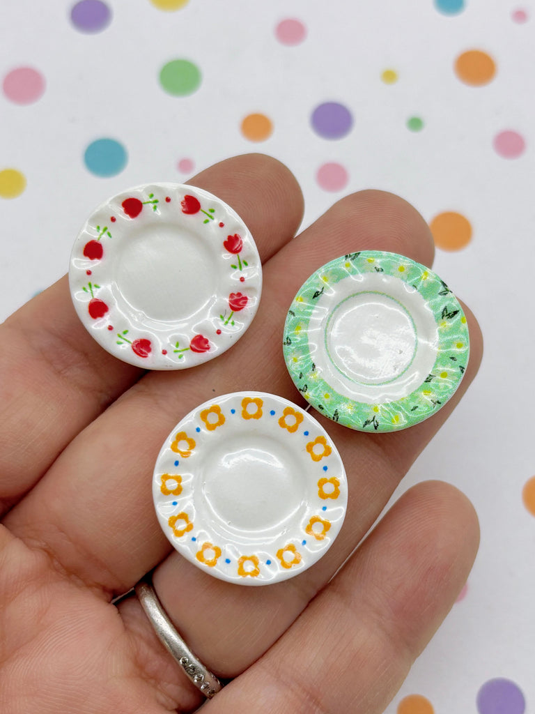 A hand holding three small, colorful plates with different patterns on them.