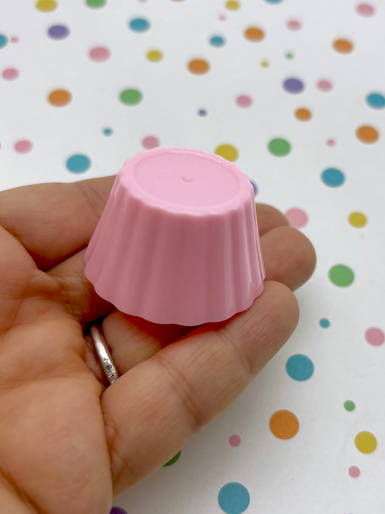 a person is holding a small pink object in their hand