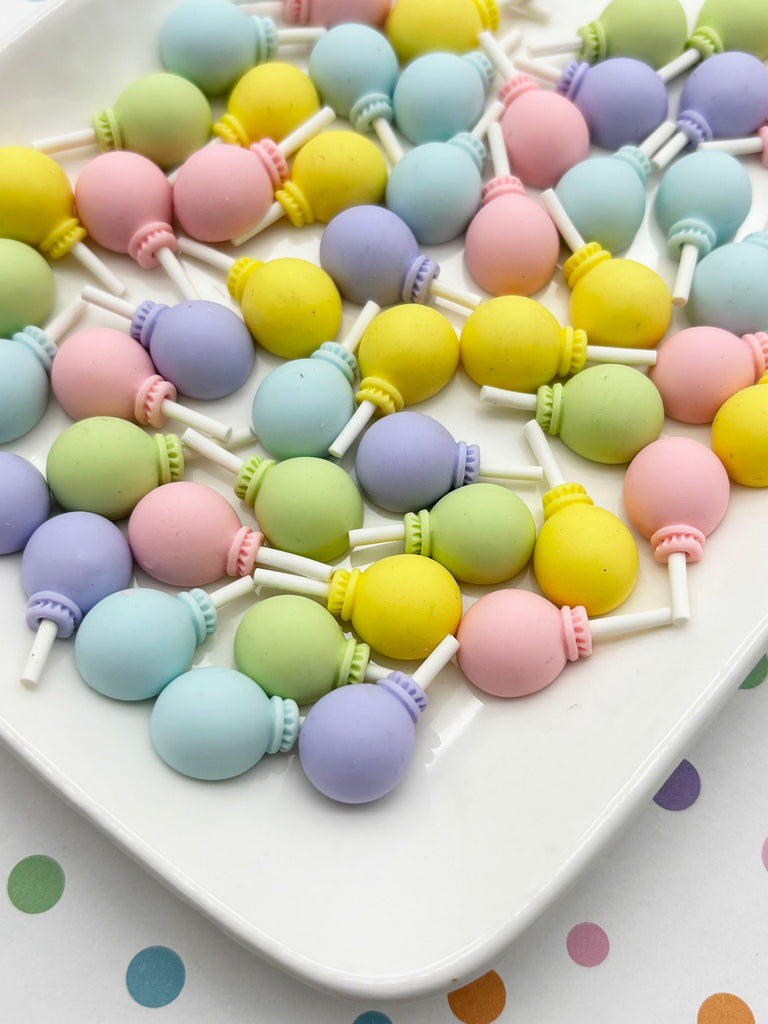 a white plate filled with colorful, pastel-colored lollipops arranged in a visually appealing manner.