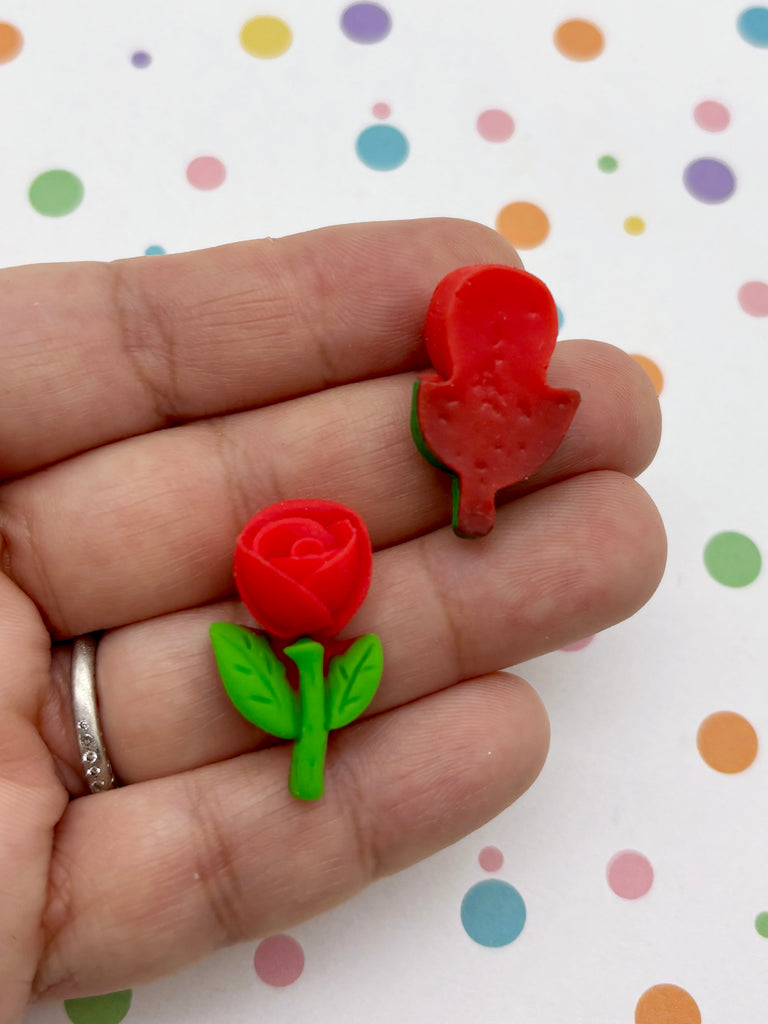 A hand holding two small, colorful objects resembling flowers against a background with polka dots.