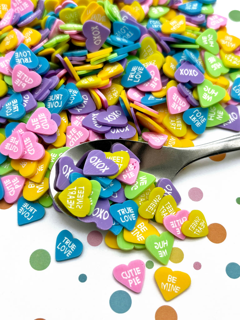 a spoon full of conversation hearts on a table