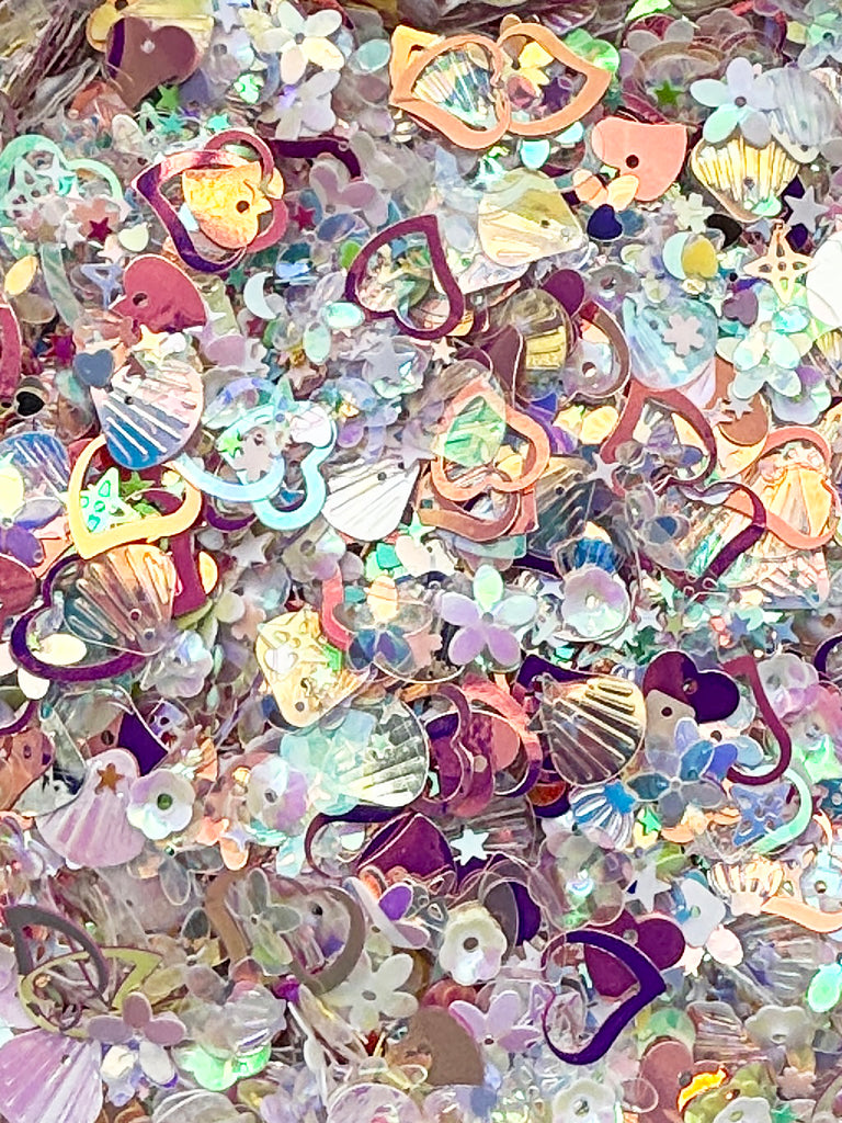 The image is a collage of various colorful and patterned sequin pieces, including hearts, flowers, and other decorative shapes.