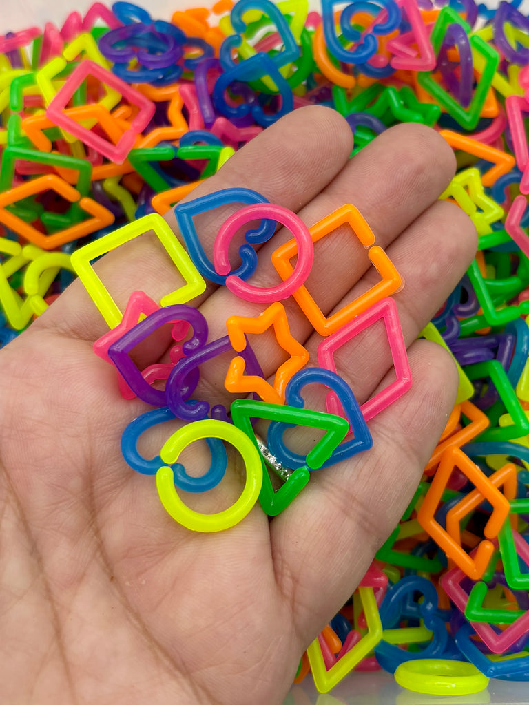 A hand holding a pile of colorful plastic shapes, including various geometric and organic forms.