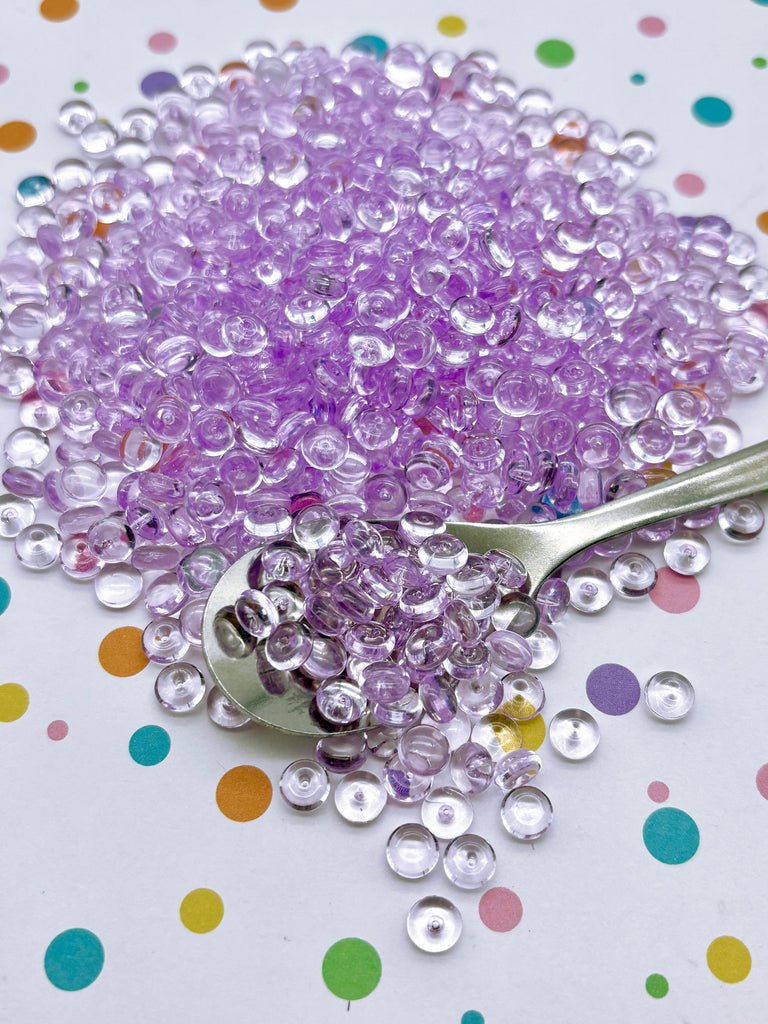 a pile of purple beads next to a spoon