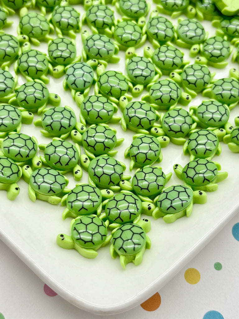 a collection of small green turtle-shaped objects arranged on a white surface.
