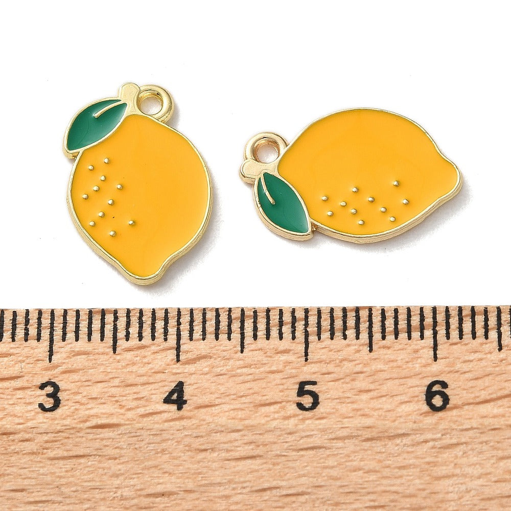 two enamel charms shaped like lemons, with a ruler placed between them to indicate their size.