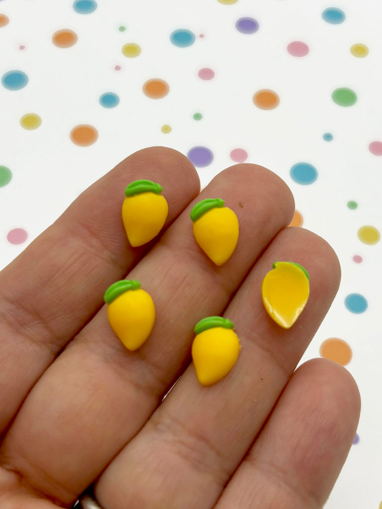 a hand holding a yellow and green pair of fruit shaped earrings