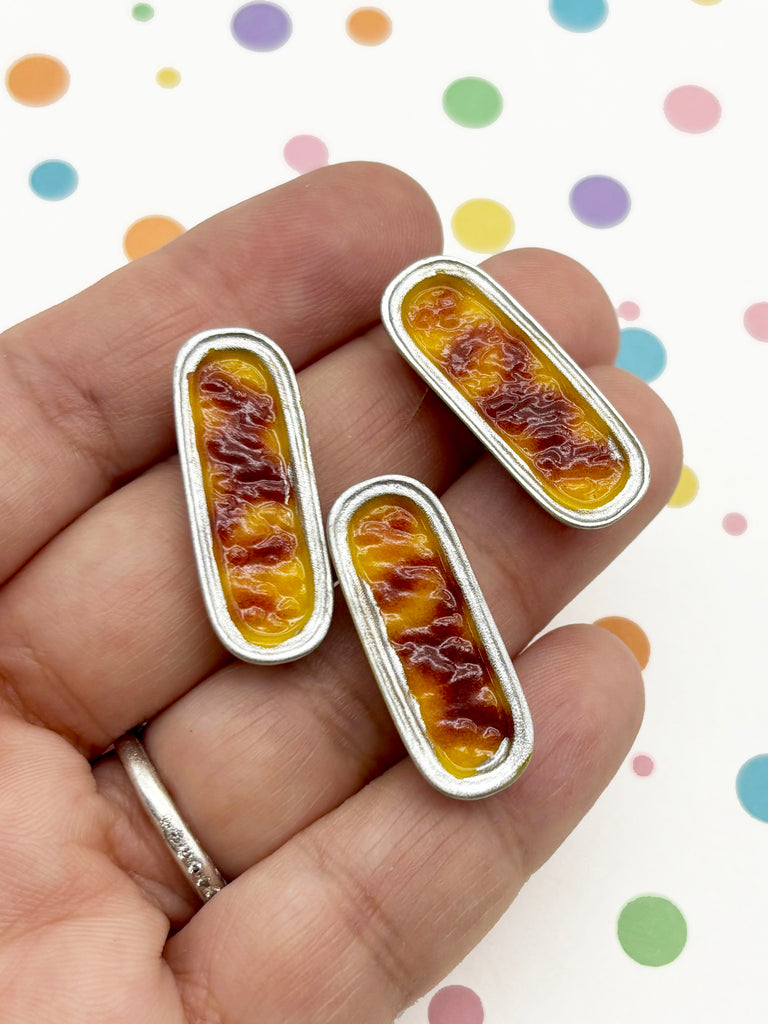 A hand holding three small, oval-shaped objects with a yellow and red color scheme, against a background with colorful polka dots.