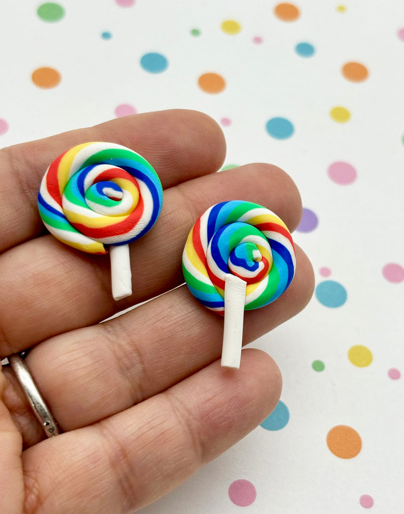 a person holding two lollipops in their hand